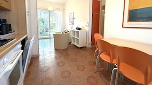 Een moderne keuken met een eethoek, een uitzicht door de glazen deur en een kunstwerk in een lijst aan de muur.