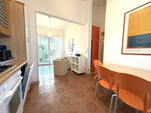 Eine moderne Küche mit Essbereich, Blick durch die Glastür und einem gerahmten Kunstwerk an der Wand.