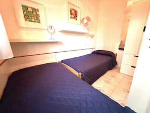 A small, compact room with two single beds, a small shelf with a mirror, and a white wardrobe. - Bright Villa With a Fenced Garden Near the Beach (San Michele al Tagliamento)