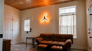 A living room with a brown leather sofa, a coffee table, and a wall-mounted light fixture.
