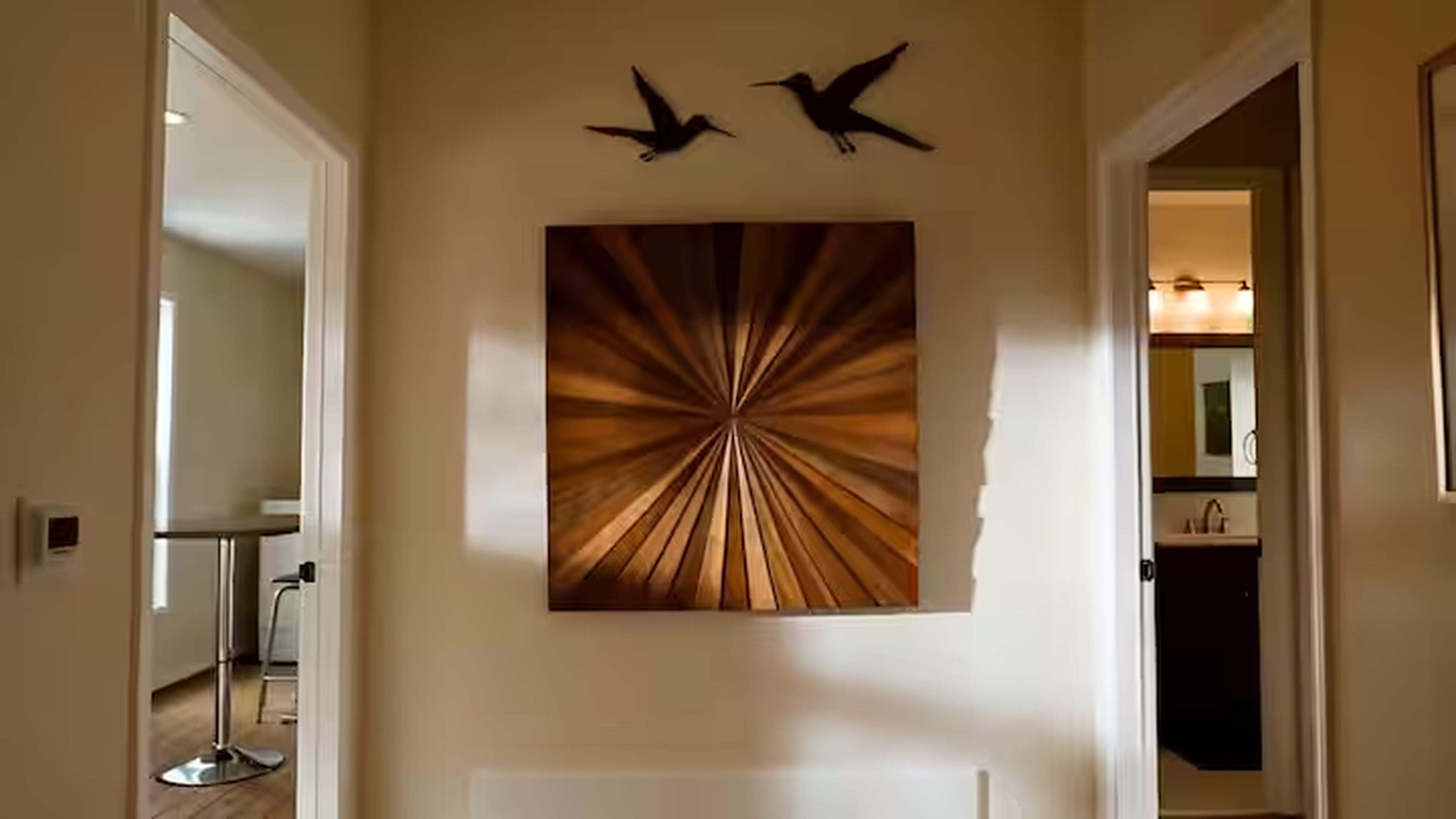 Corredor com obra de arte na parede, retratando pássaros e um padrão circular.