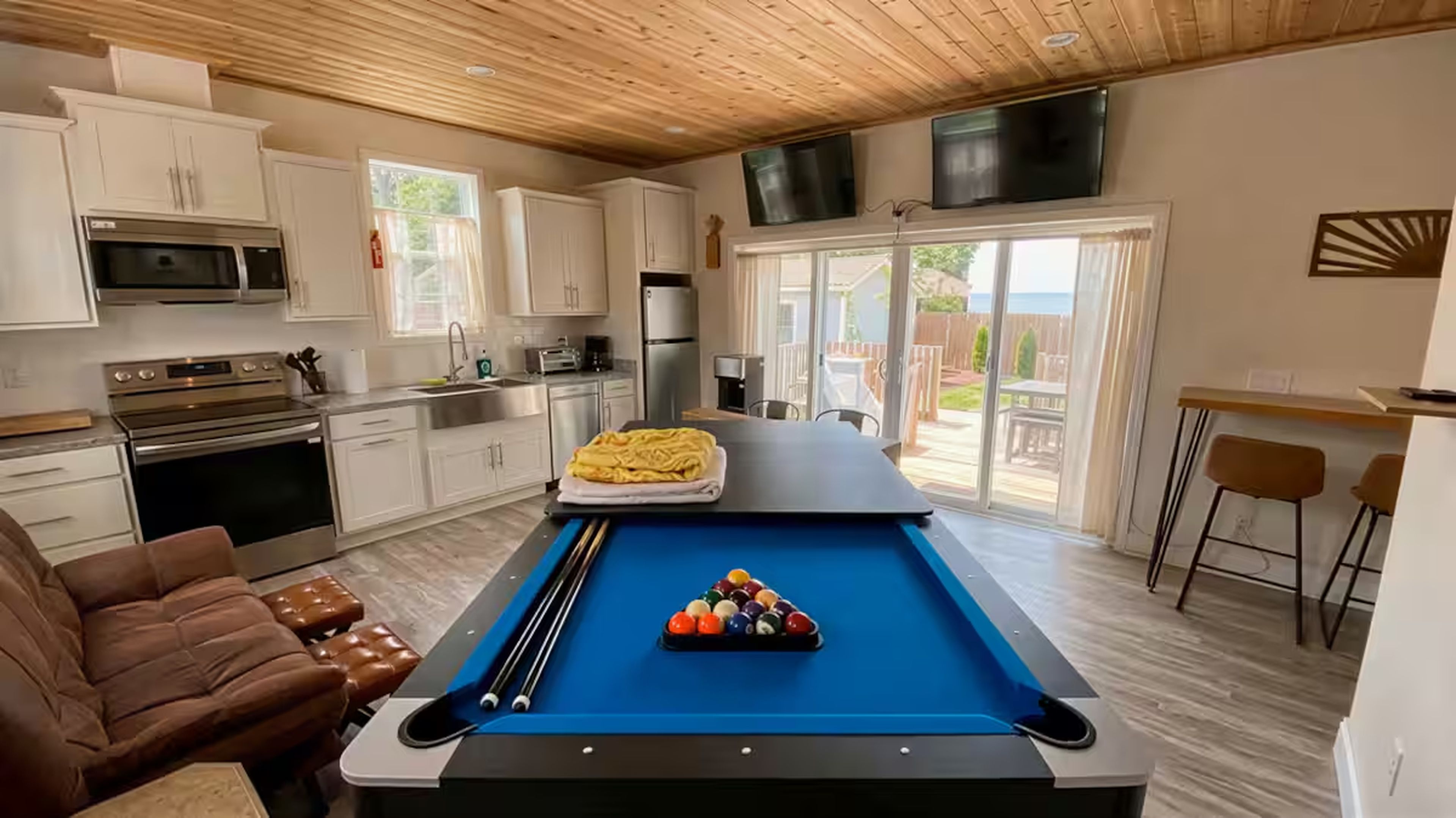 Una cocina moderna con mesa de billar, sofá de cuero marrón y comedor con vistas.