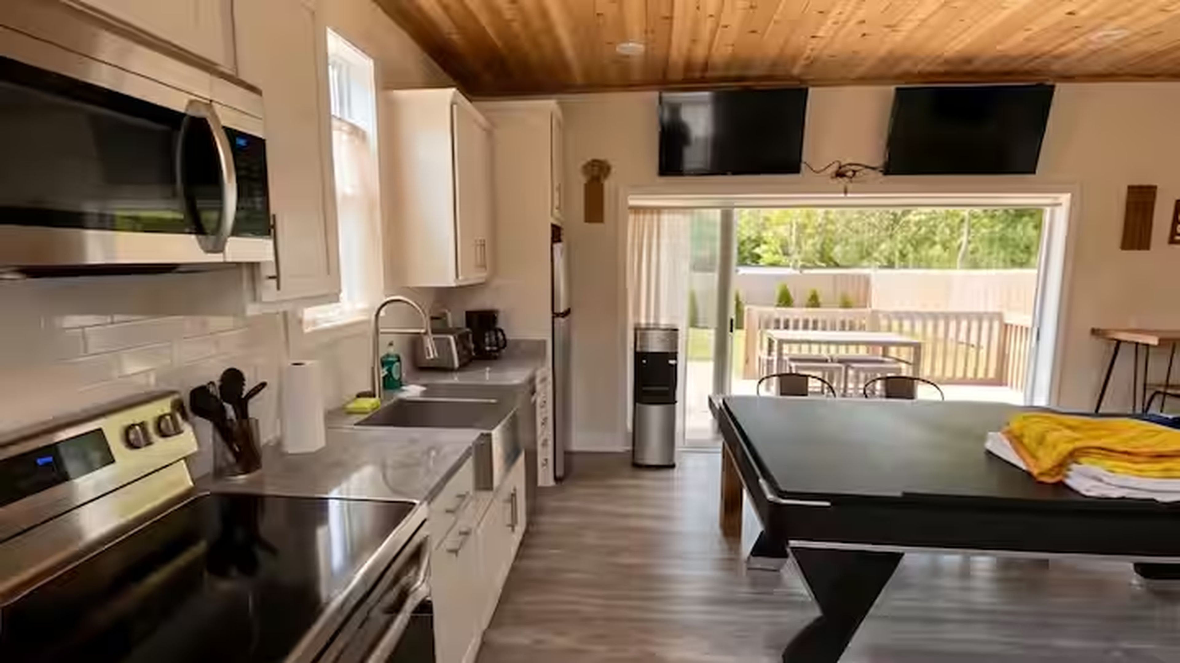 A modern kitchen with stainless steel appliances, a dining area with a table, and a sliding glass door leading to an outdoor patio.