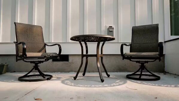 Two chairs and a table outside a building with vertical siding.