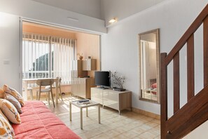 A living room with a sofa, a coffee table, a TV, a desk, and a chair. - Apartment “St Clair” with Sea View, Wi-Fi, and Air Conditioning (Le Lavandou)