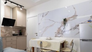 Een moderne keuken met een marmeren spatwand, een eettafel met stoelen en een ingebouwde televisie.