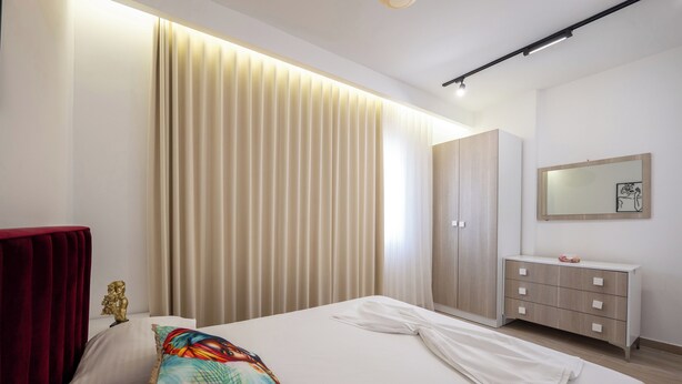 Een moderne hotelkamer met een groot bed, een garderobe en een nachtkastje.