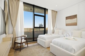 Een hotelkamer met twee bedden, een stoel, een bureau en een groot raam met uitzicht op de stad.