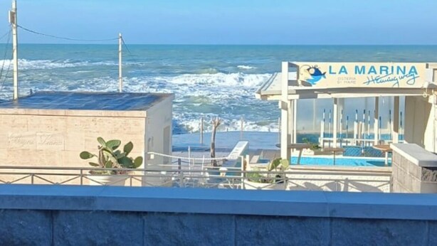 A coastal view with a building labeled "LA MARINA" featuring a pool and outdoor seating. - Lo scoglietto apartment 20 mt from the sea (Rosignano Solvay)