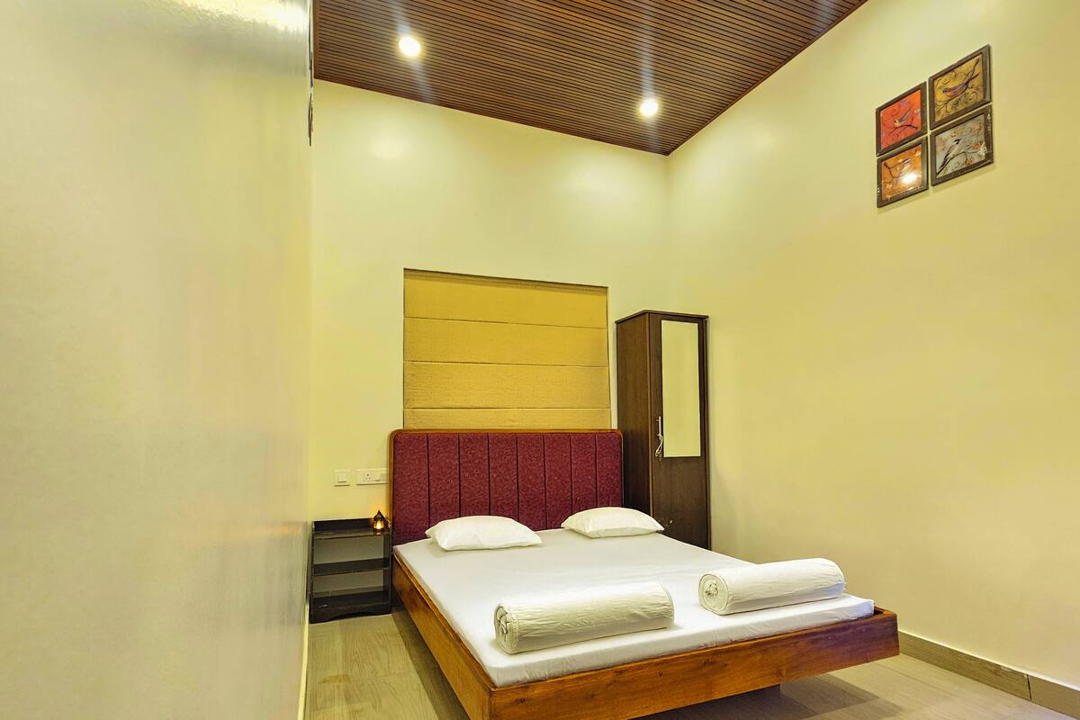 A bedroom with a wooden bed, a red headboard, a wardrobe, and a ceiling light.
