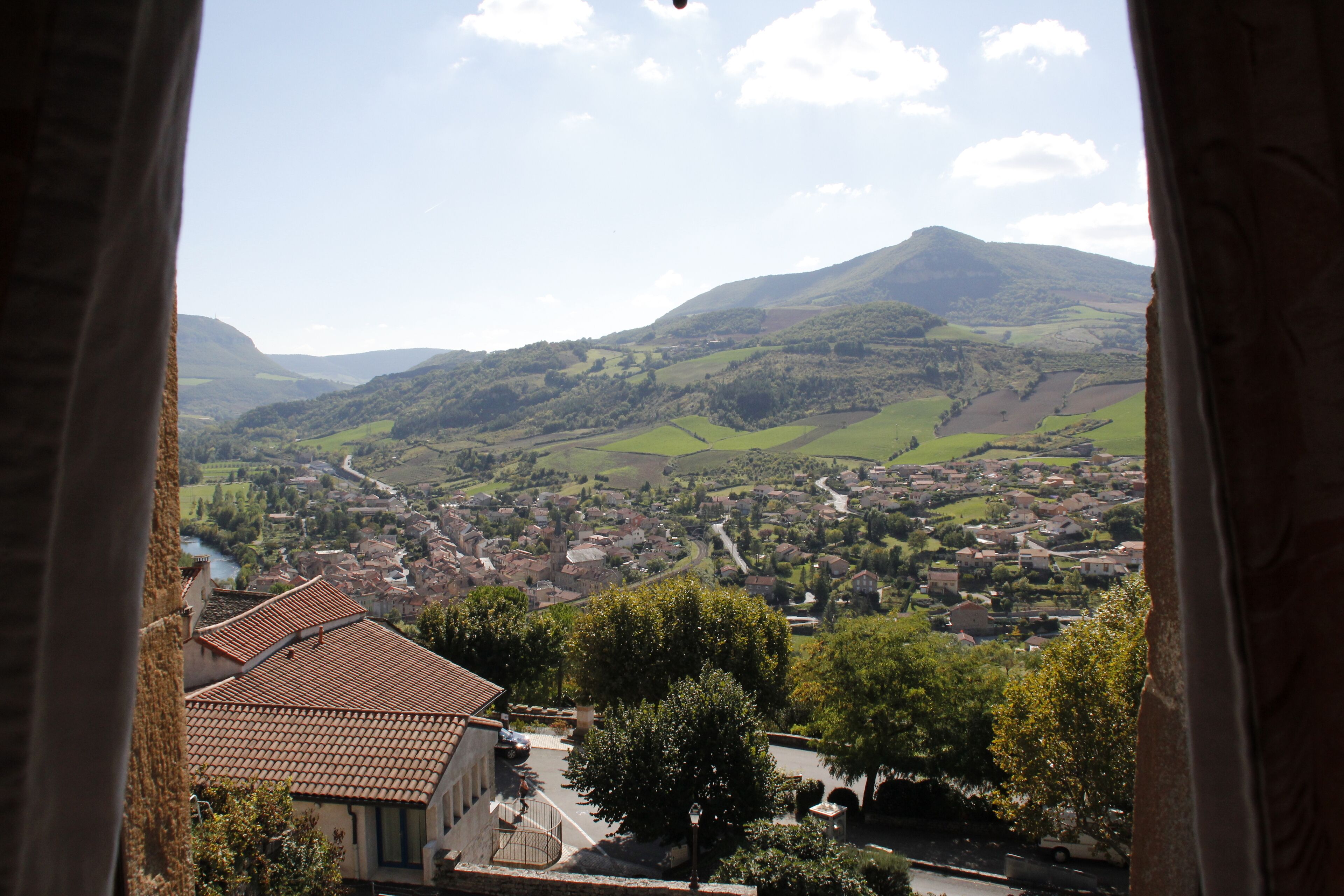 Vista de un pueblo con un río, rodeado de colinas y montañas.