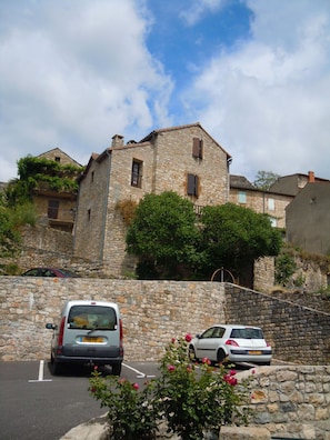 Ein Gebäude aus Stein mit geneigtem Dach, parkenden Autos und einer Steinmauer.
