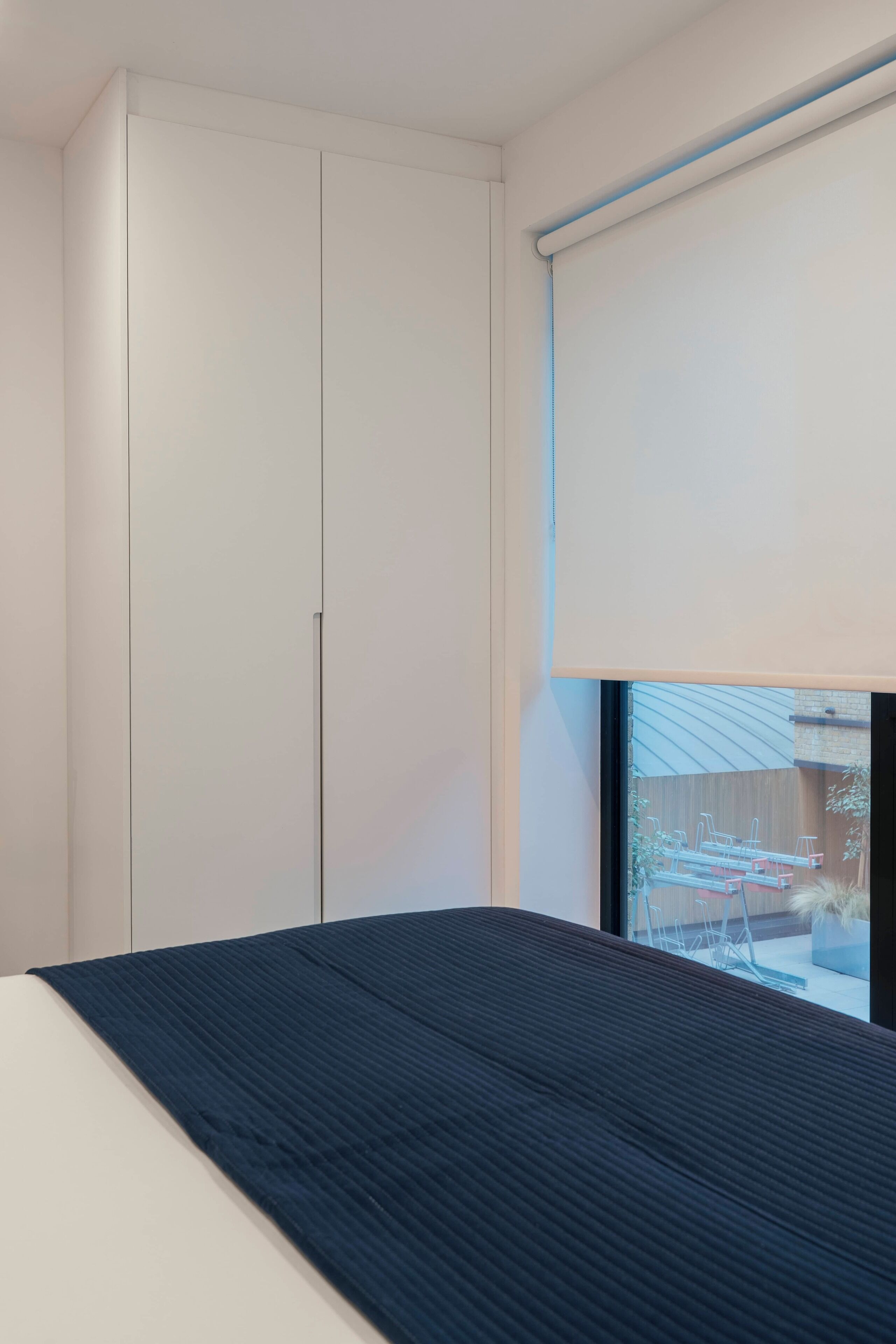 Un dormitorio con cama, armario y ventana con vistas a equipo de ejercicios al aire libre.