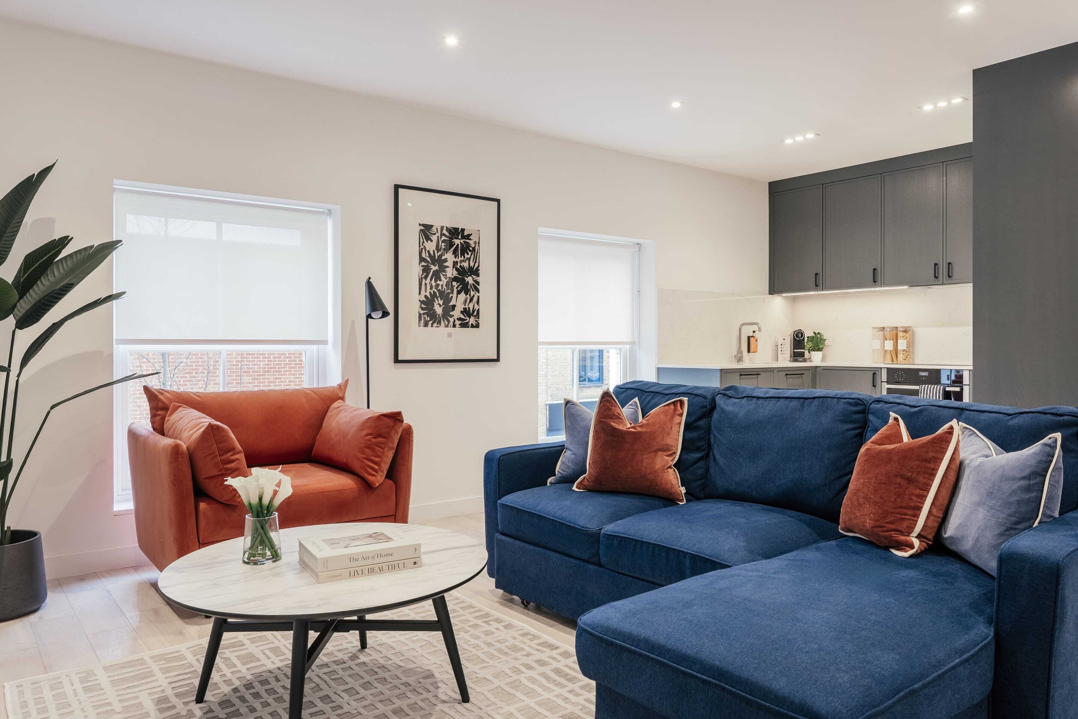 Ein modernes Wohnzimmer mit einem blauen Sofa, einem runden Couchtisch und einem Topfpflanzen.
