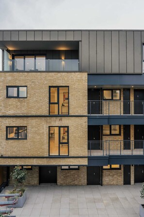 Un immeuble moderne à plusieurs étages, doté d’une façade en briques, de grandes fenêtres et d’un toit plat.