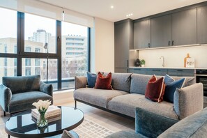 Una sala de estar moderna con un sofá gris, una mesa de centro y una estantería.