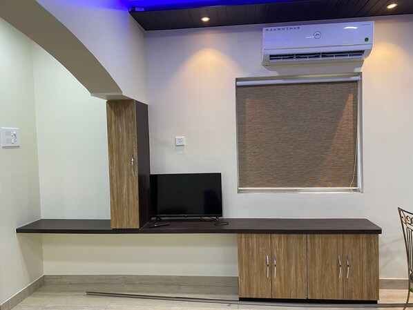 A modern kitchen with a built-in stove, a flat-screen TV, and wooden cabinets. - Kiana's Funstay (Lonavala)