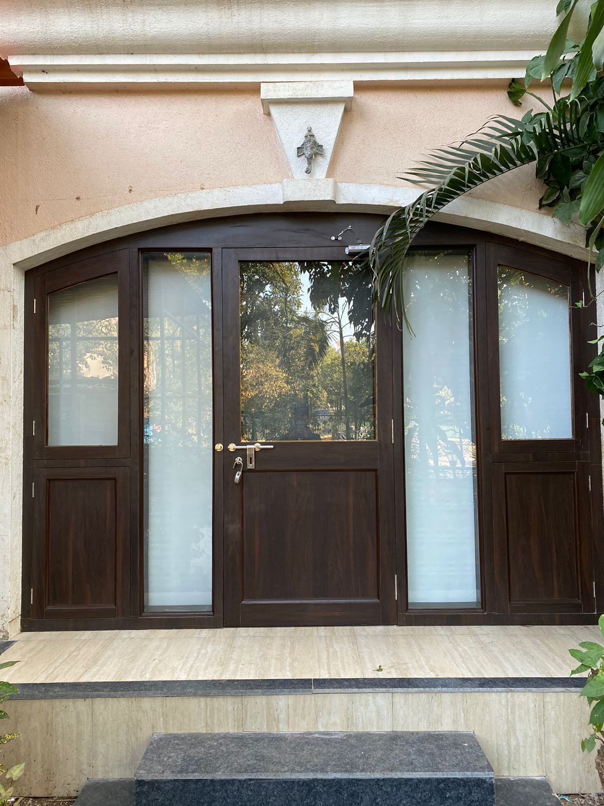 A large, dark wooden door with frosted glass panels and a central door.