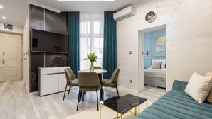 A modern living room with a sofa, a coffee table, and a dining area with chairs and a table. - Native Apartments Kołłątaja 12 (Kraków)