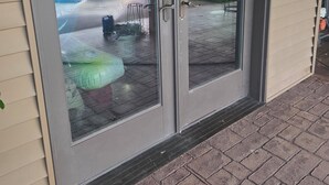 Une porte-fenêtre coulissante donnant sur un patio aménagé dans le jardin.