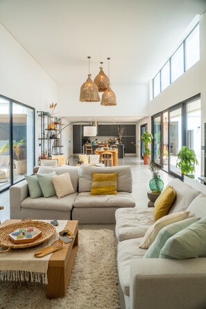 A modern living room with a sectional sofa, a coffee table, and a dining area in the background. - Setúbal & Lisbon Dream Getaway - Villa do Sol (Fernão Ferro)