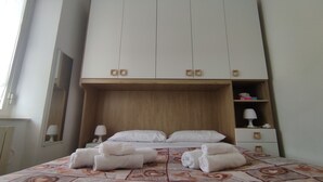 Habitación de hotel con una cama grande, dos mesitas de noche, un armario y una ventana.