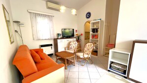 A living room with a sofa, two chairs, a TV, and a bookshelf. - Relaxing Villa With Private Garden in Nature (San Michele al Tagliamento)