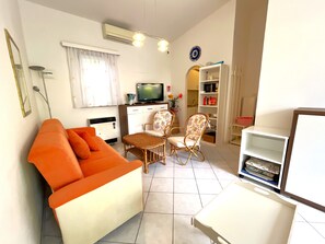 A living room with a sofa, two chairs, a TV, and a bookshelf. - Relaxing Villa With Private Garden in Nature (San Michele al Tagliamento)