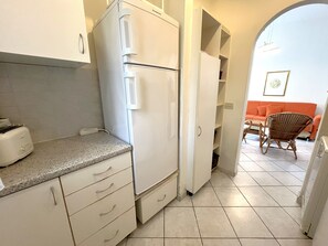 A compact kitchen with a built-in refrigerator, a toaster, and a small countertop. - Relaxing Villa With Private Garden in Nature (San Michele al Tagliamento)