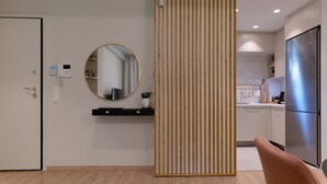 Eine moderne Küche mit einem Edelstahlkühlschrank, einer Holzabtrennung und einem runden Spiegel an der Wand.