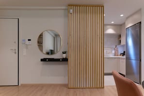 A modern kitchen with a stainless steel refrigerator, a wooden partition, and a round mirror on the wall. - Acropolis Deluxe 1BR Apartment (Athens)