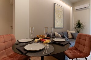 A dining table set with plates, cutlery, and glasses, surrounded by plush chairs. - Acropolis Deluxe 1BR Apartment (Athens)