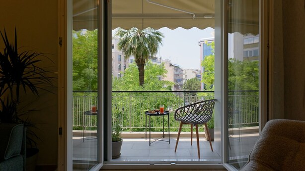 Ein Balkon mit Tisch, Stühlen und einem Blumentopf.