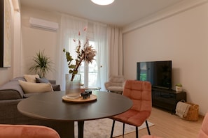 A modern living room with a round table, a sofa, a chair, a TV, and a plant. - Acropolis Deluxe 1BR Apartment (Athens)
