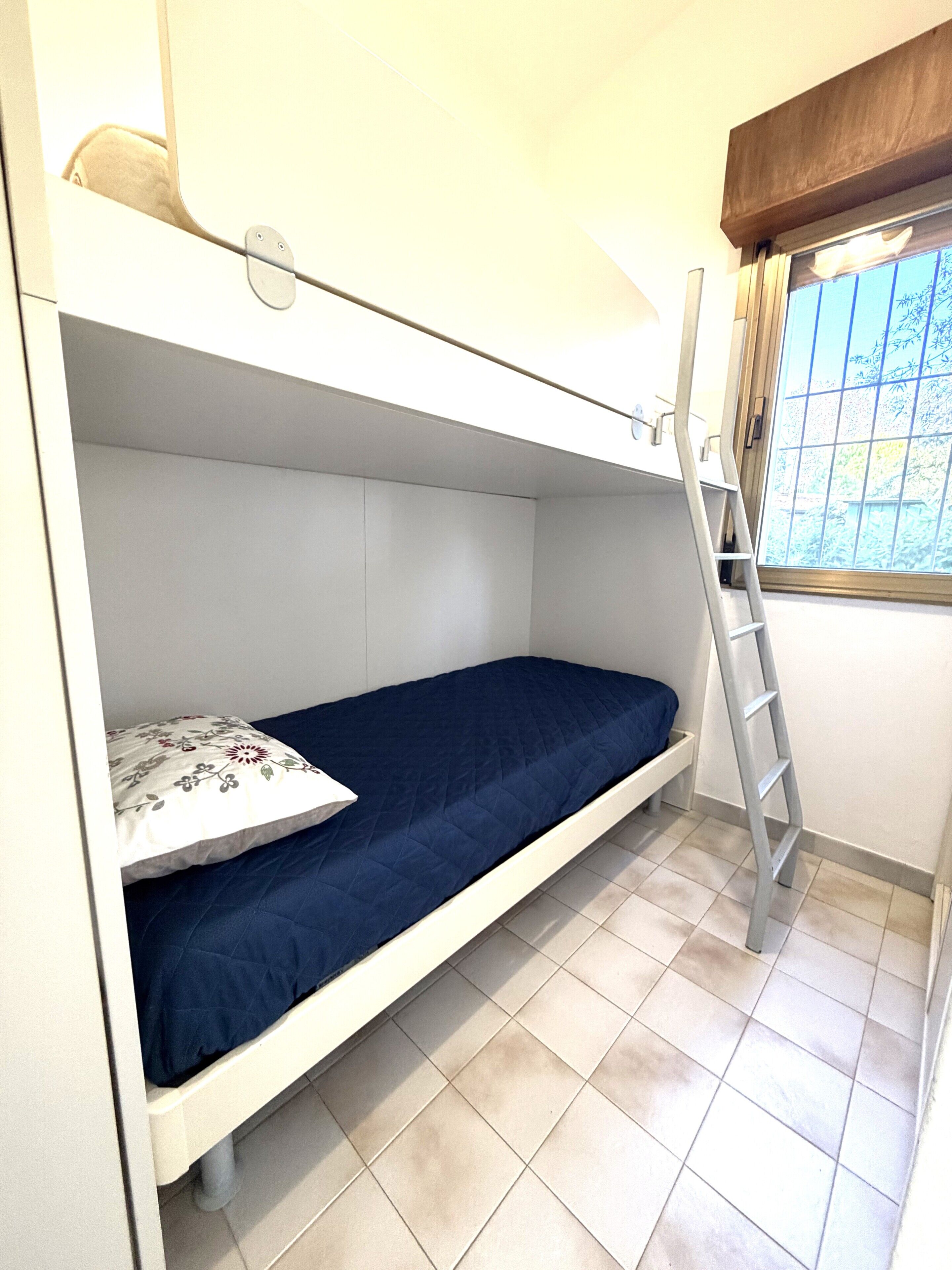 A small, single-bed room with a ladder for access to the upper bunk.
