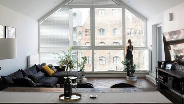 Una sala de estar moderna con un ventanal grande, un sofá, una mesa de centro y un televisor.