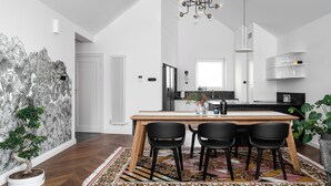 Una cocina moderna con una mesa de madera y sillas negras, una lámpara de araña y una planta en maceta.