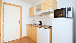A compact kitchen with wooden cabinets, a microwave, a coffee maker, and a dishwasher. - Apartment in Orelle Near 3 Vallees Ski Area (Orelle)