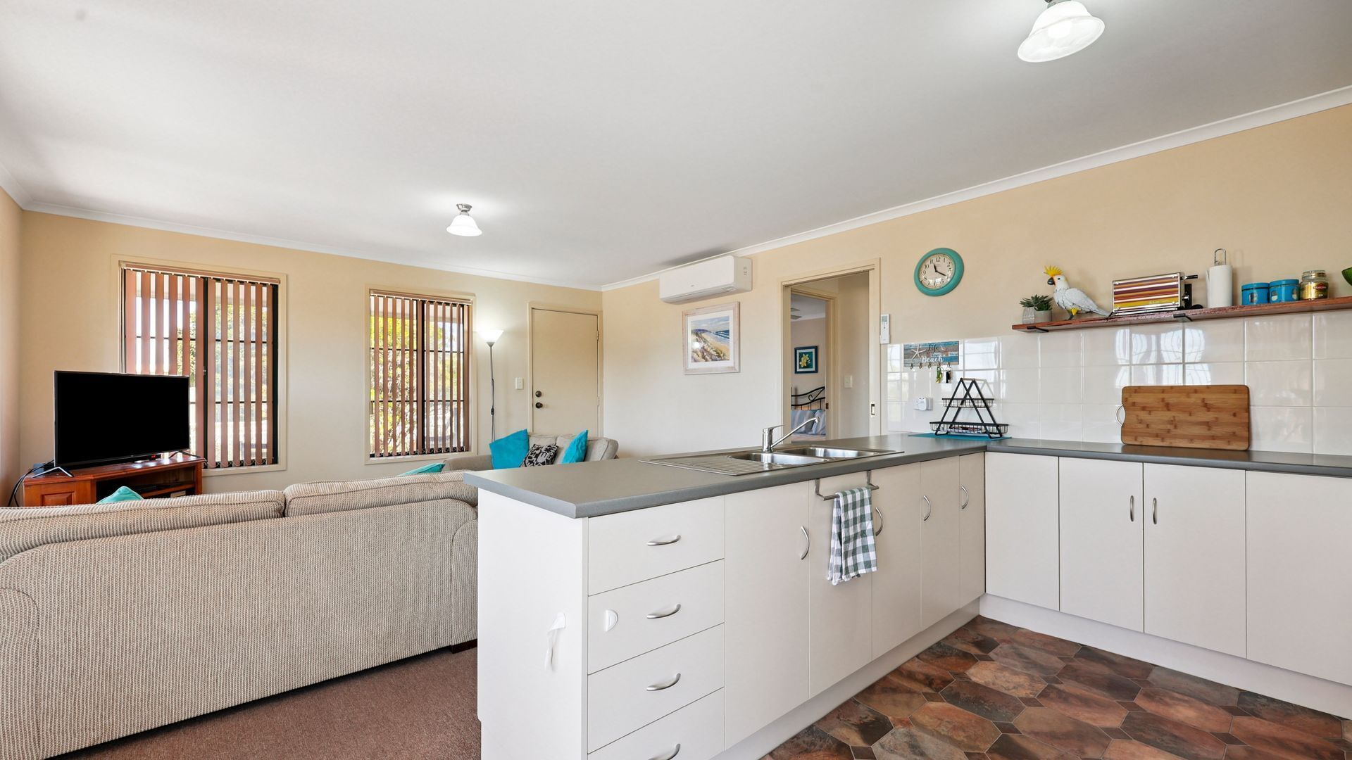 A compact living space with a kitchenette, a sofa, and a TV.