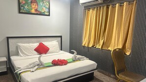 A hotel room with a bed, a chair, a painting, and a window with curtains. - Hotel Vaishnavi (Hyderabad)
