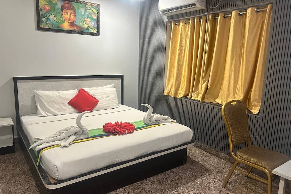 A hotel room with a bed, a chair, a painting, and a window with curtains.