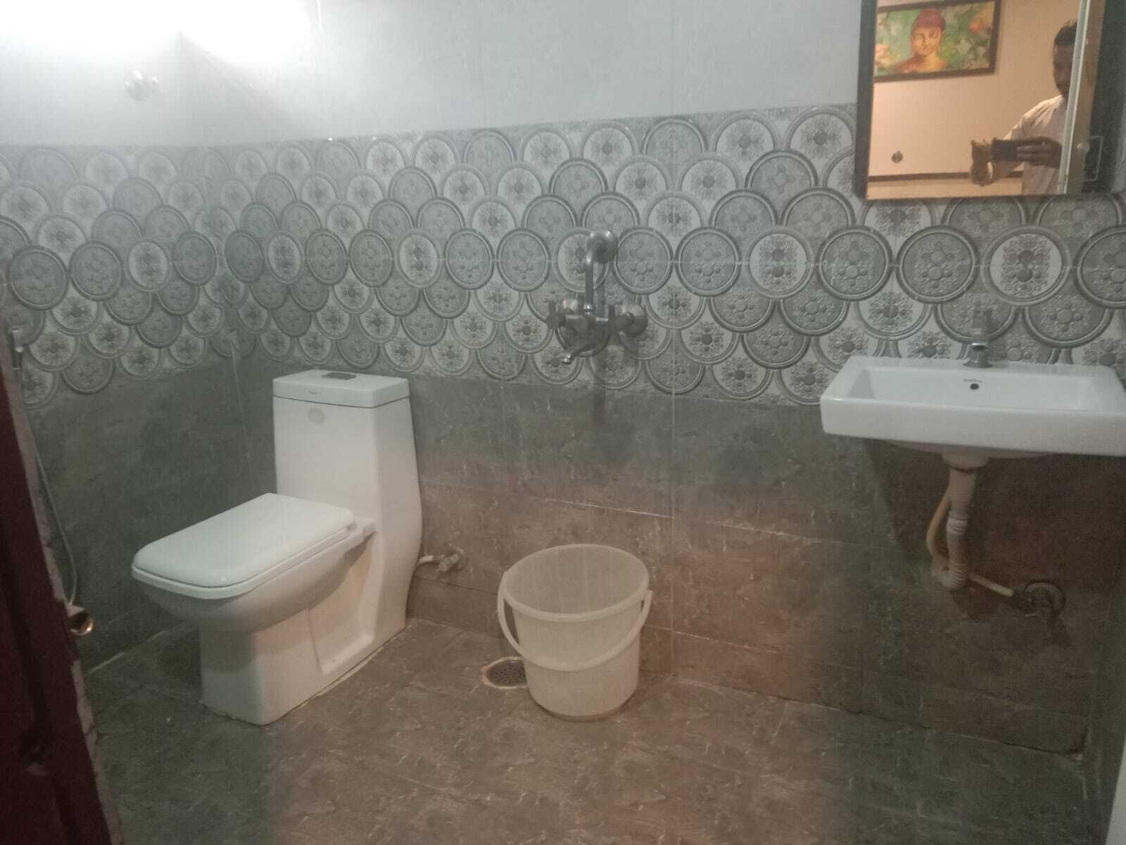 Un baño con inodoro, lavamanos y pared decorada con azulejos.