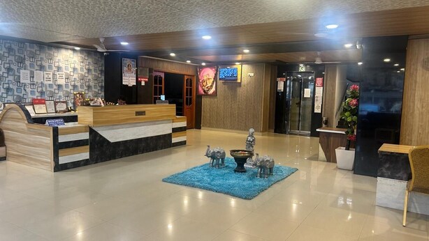 A hotel lobby with a reception desk, a blue carpet, and decorative elephant statues. - Hotel Vaishnavi (Hyderabad)