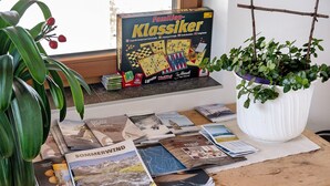Ein Tisch mit Gesellschaftsspielen, Zeitschriften und einer Topfpflanze.