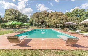 Ein rechteckiger Pool mit gefliestem Sonnendeck, umgeben von Liegestühlen und Sonnenschirmen.