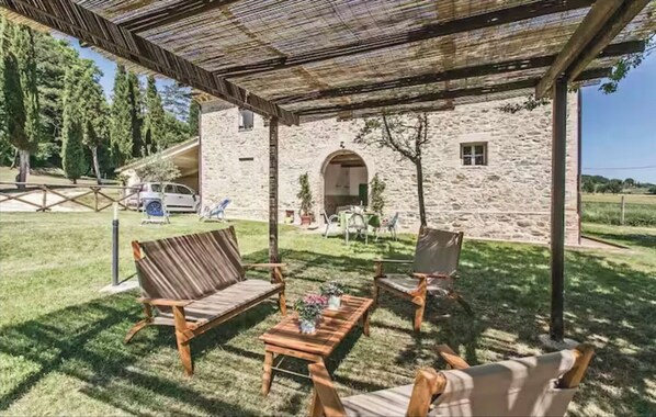 A stone building with a covered patio area featuring wooden furniture and a table. - Anemone - Characteristic farmhouse (Poggio delle Corti)