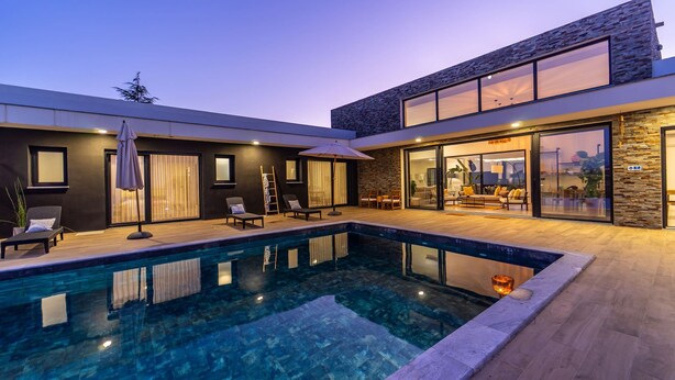 A modern house with a swimming pool, outdoor seating, and a large glass door leading to a living area. - Setubal Lisbon Dream Getaway Villa do Sol (Seixal)