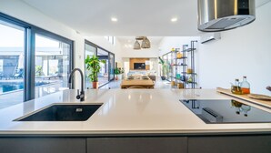 A modern kitchen with a large island, stainless steel appliances, and a view of the outdoors. - Setubal Lisbon Dream Getaway Villa do Sol (Seixal)