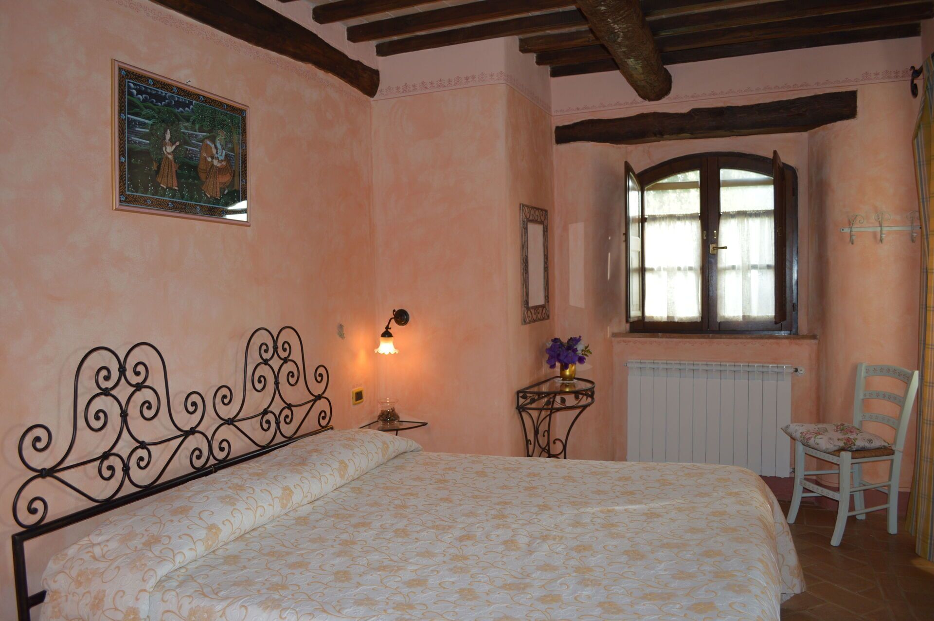 A bedroom with a bed, a window, a chair, and a wall-mounted lamp.
