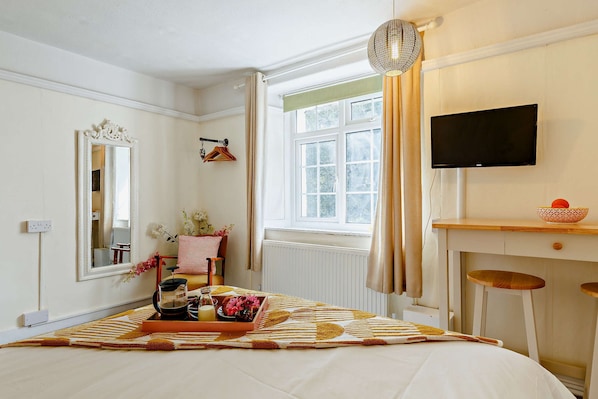 A bedroom with a bed, a dresser, a television, a window with curtains, and a mirror. - 1605 by the sea (Falmouth)